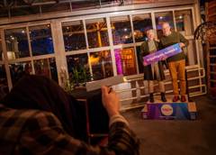 Twee personen met bord “Vrijwilligers, bedankt!” tijdens een feestelijke bijeenkomst.