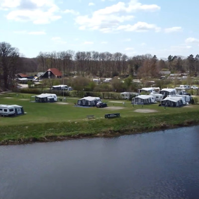Vakantiepark aan het water met caravans en tenten