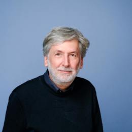Portretfoto van Geert Boogaard voor een blauwe achtergrond