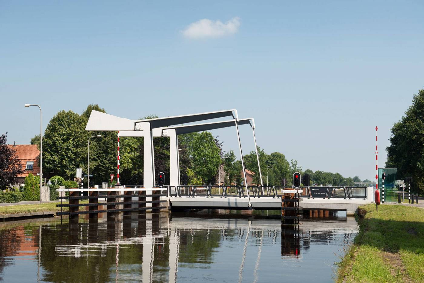 Witte ophaalbrug over een kanaal in een groene omgeving.