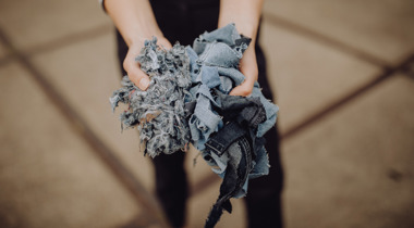 Handen die gescheurde stukken spijkerstof vasthouden