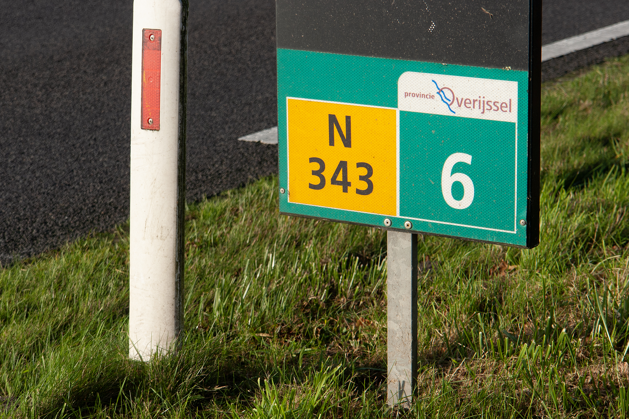 Hectometerbordje van de N343 in de berm, daarnaast nog een paaltje met een reflector