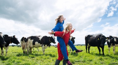 Twee kinderen in overalls in weiland tussen koeien