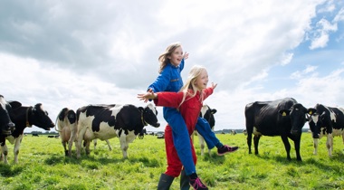 Twee kinderen in overalls in weiland tussen koeien