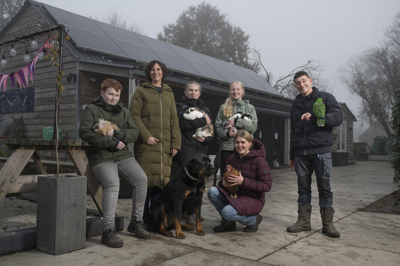 Vijf jonge vrijwilligers en voorzitter Magryt Keuning van Flappus met diverse dieren bij de dierenopvang in Zwolle.