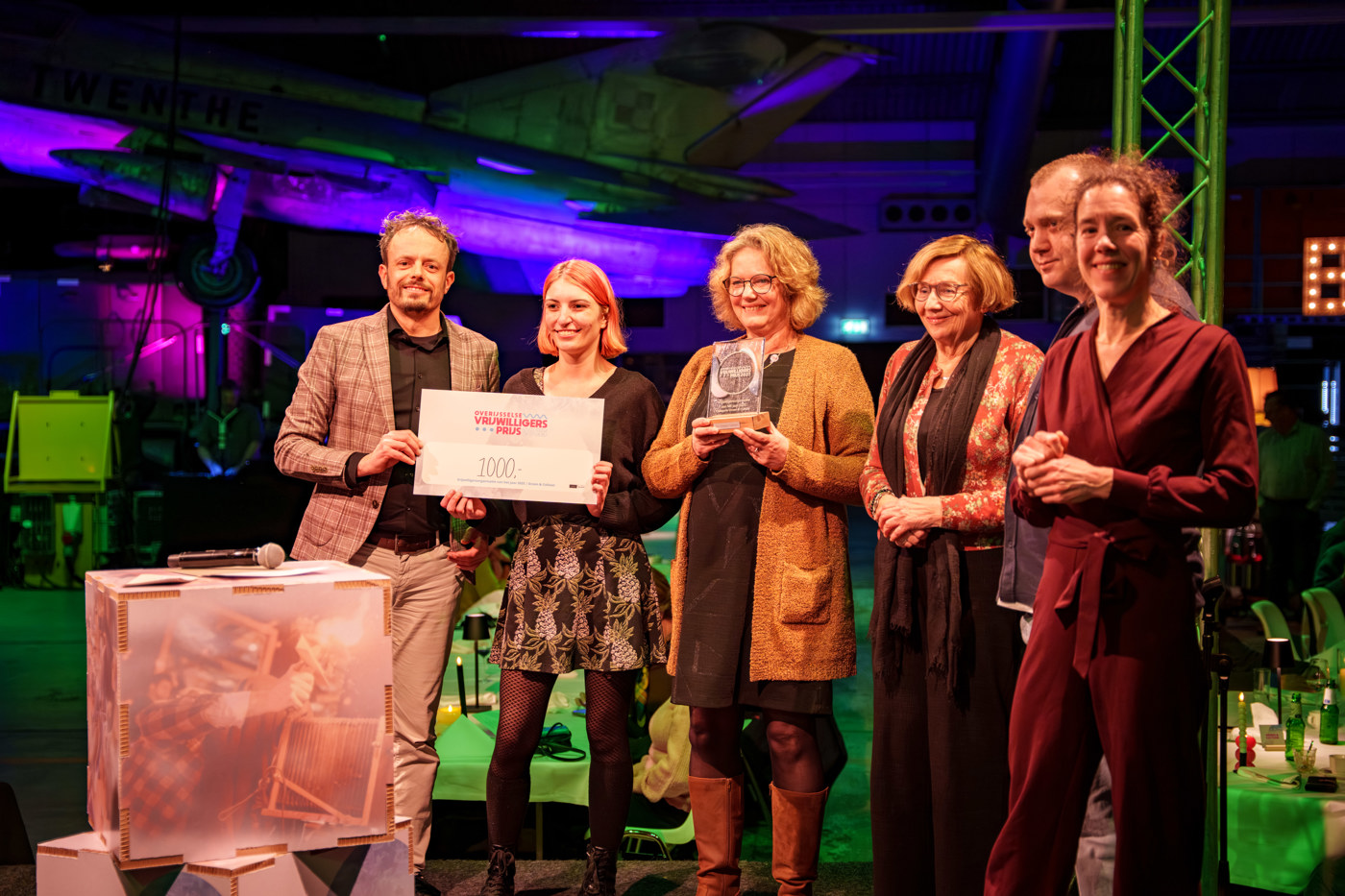 Gedeputeerde Tijs de Bree overhandigt het geldbedrag aan vijf mensen van een vrijwilligersorganistie, een van hen heeft de award al ontvangen.