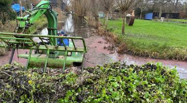 Amfibievoertuig verwijdert waterplanten uit een sloot