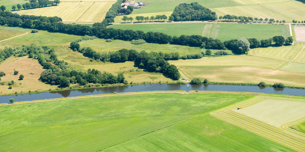 vogelperspectief van landschap van struiken en bomen met een rivier erdoor 