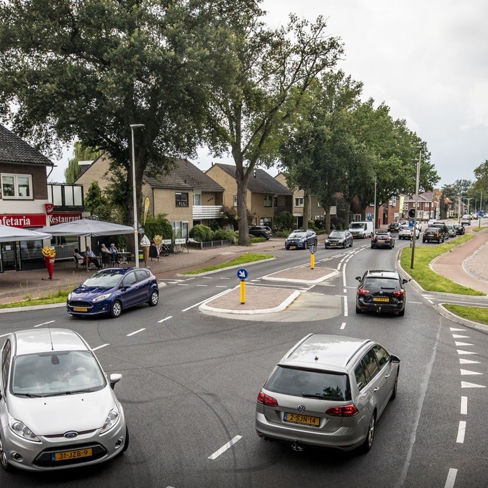 Auto's op een kruispunt in Weerselo (IJssalon op de hoek, rij huizen daarnaast)