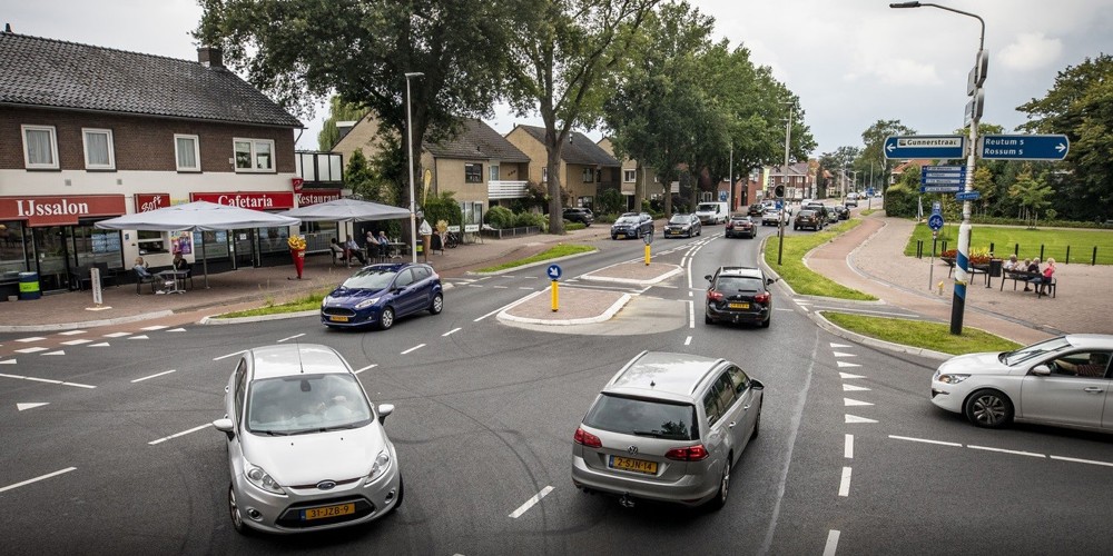 Auto's op een kruispunt in Weerselo (IJssalon op de hoek, rij huizen daarnaast)