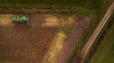 tractor in veld maait weiland foto van bovenaf