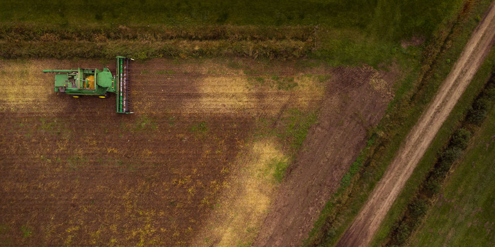 tractor in veld maait weiland foto van bovenaf