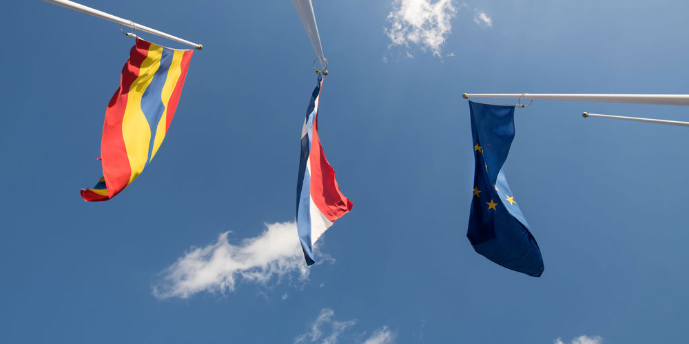 drie vlaggen: de Overijsselse, Nederlandse en Europese