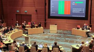 Overzicht van de Statenzaal met stemuitslag op groot scherm.