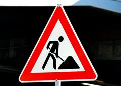  Een verkeersbord in de vorm van een rode driehoek met een wit veld en een zwart pictogram van een persoon die aan het scheppen is.