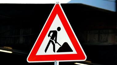  Een verkeersbord in de vorm van een rode driehoek met een wit veld en een zwart pictogram van een persoon die aan het scheppen is.