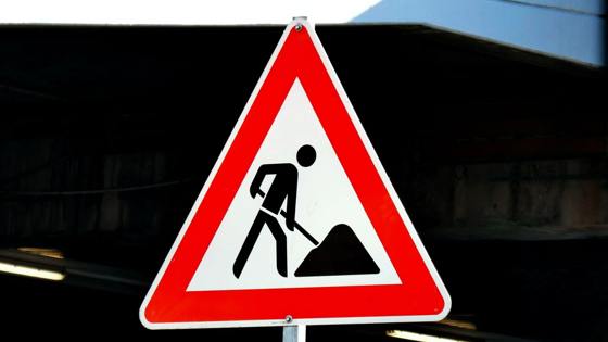  Een verkeersbord in de vorm van een rode driehoek met een wit veld en een zwart pictogram van een persoon die aan het scheppen is.