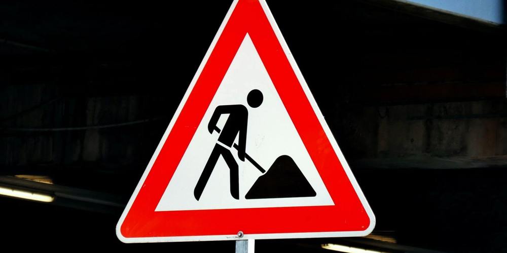  Een verkeersbord in de vorm van een rode driehoek met een wit veld en een zwart pictogram van een persoon die aan het scheppen is.