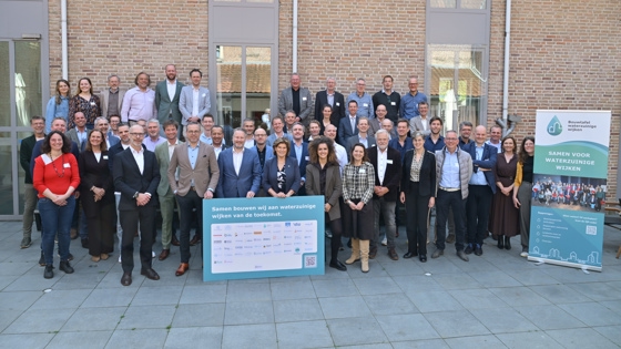 Vertegenwoordigers van de organisaties die het manifest hebben ondertekend op een groepsfoto voor een muur van een gebouw. Voor hen staat een bord met de tekst "Samen bouwen wij aan waterzuinige wijken van de toekomst." En daaronder de namen van de ondertekenaars (niet goed leesbaar op de foto). Rechts naast hen staat een bord van de Bouwtafel waterzuinige wijken met de tekst "Samen voor waterzuinige wijken."