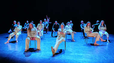 Groep mensen in witte kleren geposeerd op stoel op podium