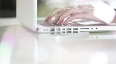 Handen die typen op witte laptop