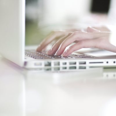 Handen die typen op witte laptop
