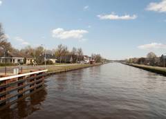 Kanaal met huizen, bomen en een ruiter op een zonnige dag.