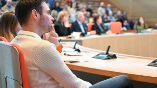 Man luistert aandachtig tijdens een bijeenkomst in een vergaderzaal