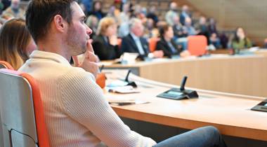 Man luistert aandachtig tijdens een bijeenkomst in een vergaderzaal