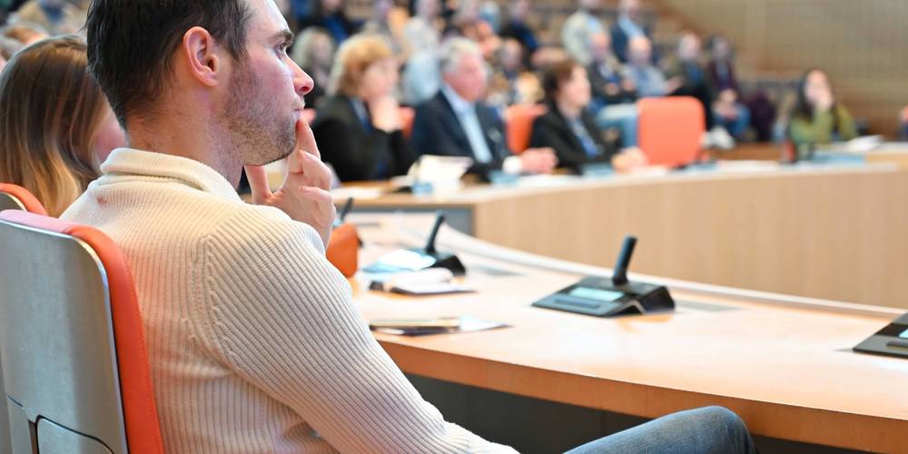 Man luistert aandachtig tijdens een bijeenkomst in een vergaderzaal