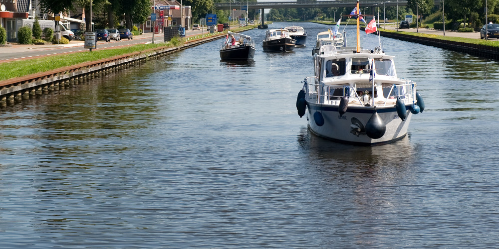 Foto van boten op brede sloot tussen woonwijk