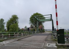 Hoogwegbrug Ossenzijl: ophaalbrug over een kanaal met bomen en een huis op de achtergrond.