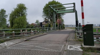 Hoogwegbrug Ossenzijl: ophaalbrug over een kanaal met bomen en een huis op de achtergrond.