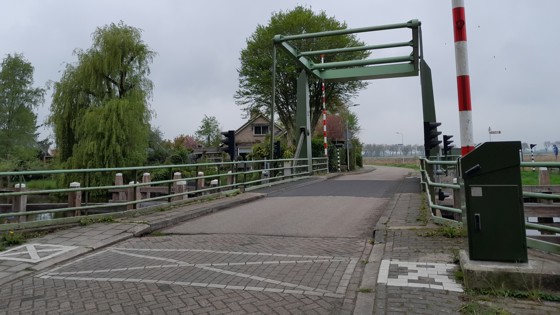 Hoogwegbrug Ossenzijl: ophaalbrug over een kanaal met bomen en een huis op de achtergrond.