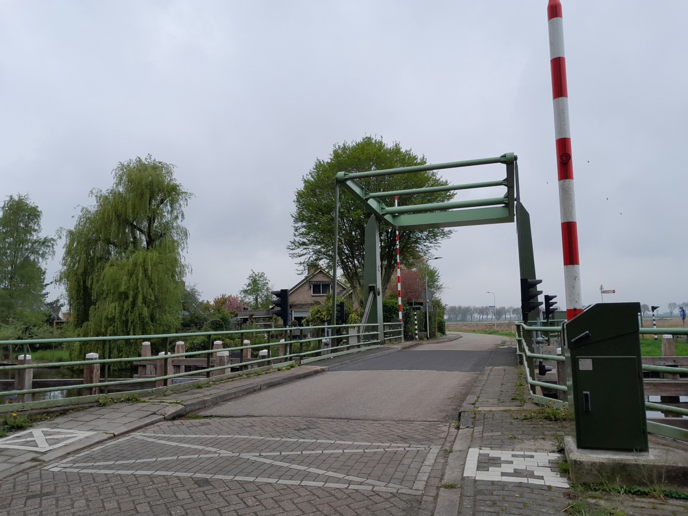 Hoogwegbrug Ossenzijl: ophaalbrug over een kanaal met bomen en een huis op de achtergrond.