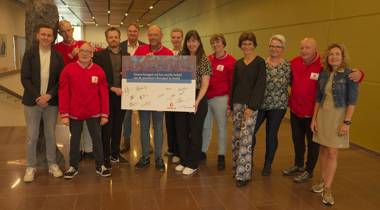 Een groep mensen, deels gekleed in rode jassen van Special TV, poseert met een groot, ondertekend bord van SpecialTV in het provinciehuis van provincie Overijssel.