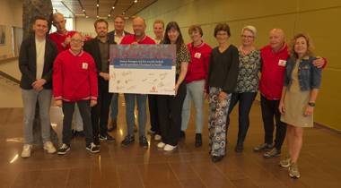 Een groep mensen, deels gekleed in rode jassen van Special TV, poseert met een groot, ondertekend bord van SpecialTV in het provinciehuis van provincie Overijssel.