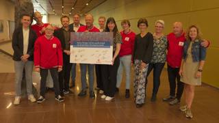 Een groep mensen, deels gekleed in rode jassen van Special TV, poseert met een groot, ondertekend bord van SpecialTV in het provinciehuis van provincie Overijssel.