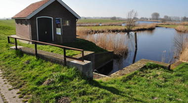 Huisje met trappetje naast een sloot in natuurgebied