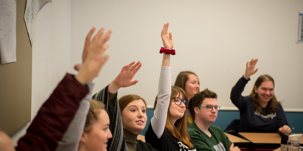 Jongeren in een klas die de hand opsteken