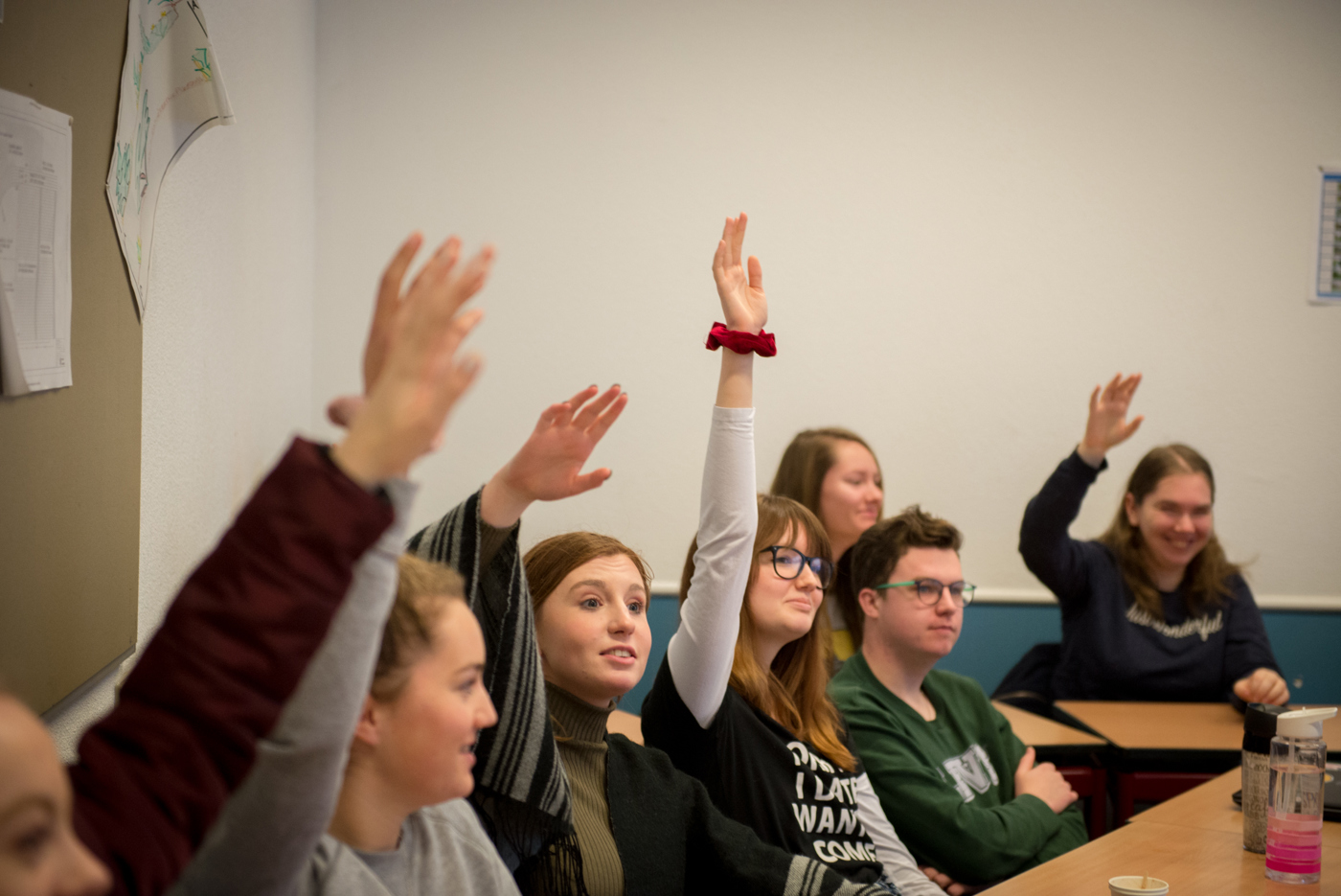 Jongeren in een klas die de hand opsteken
