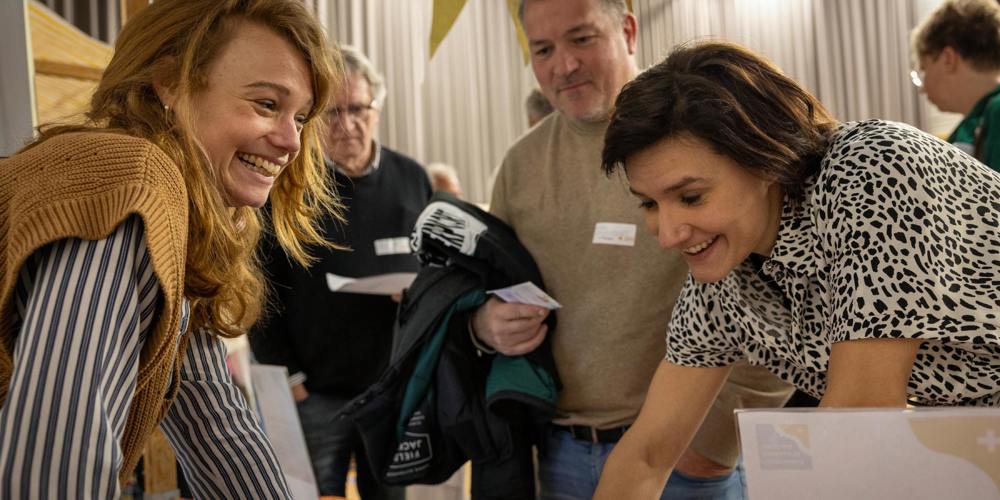Twee vrouwen lachen en praten aan een informatiestand op Fondsen Festival