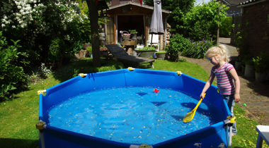 Kind met blauw zwembadje in tuin