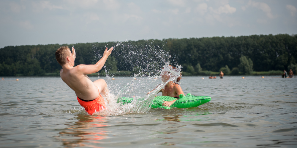 mensen die zwemmen in een natuurlijke plas met krokodil floatie