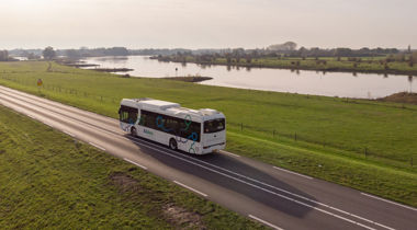 Bus op een verkeersweg tussen weilanden