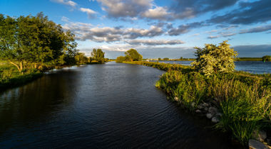 Foto van brede rivier met groene oevers