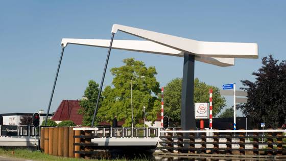 Moderne witte ophaalbrug over een kanaal bij een dorpsstraat.