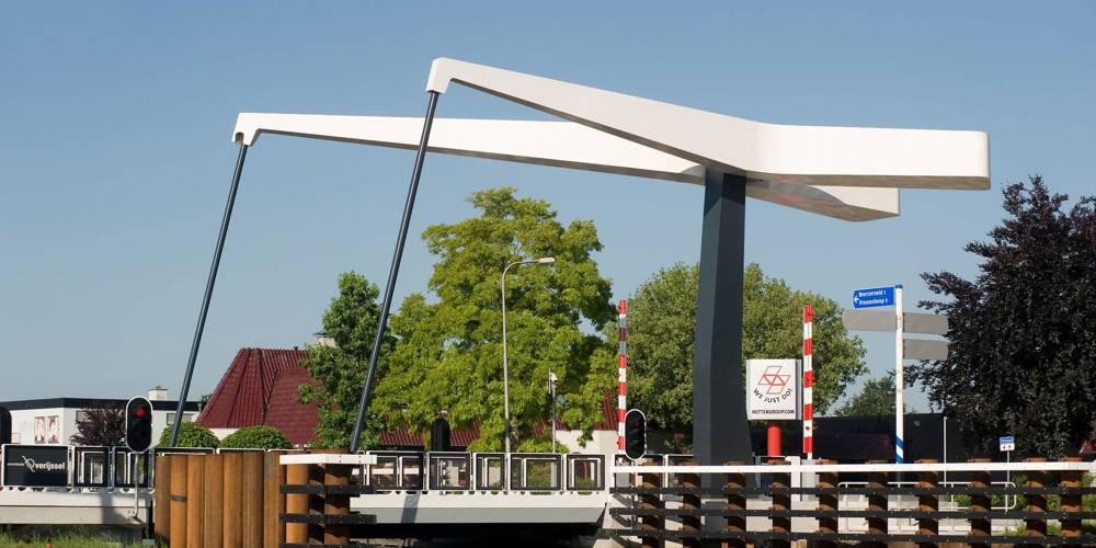 Moderne witte ophaalbrug over een kanaal bij een dorpsstraat.