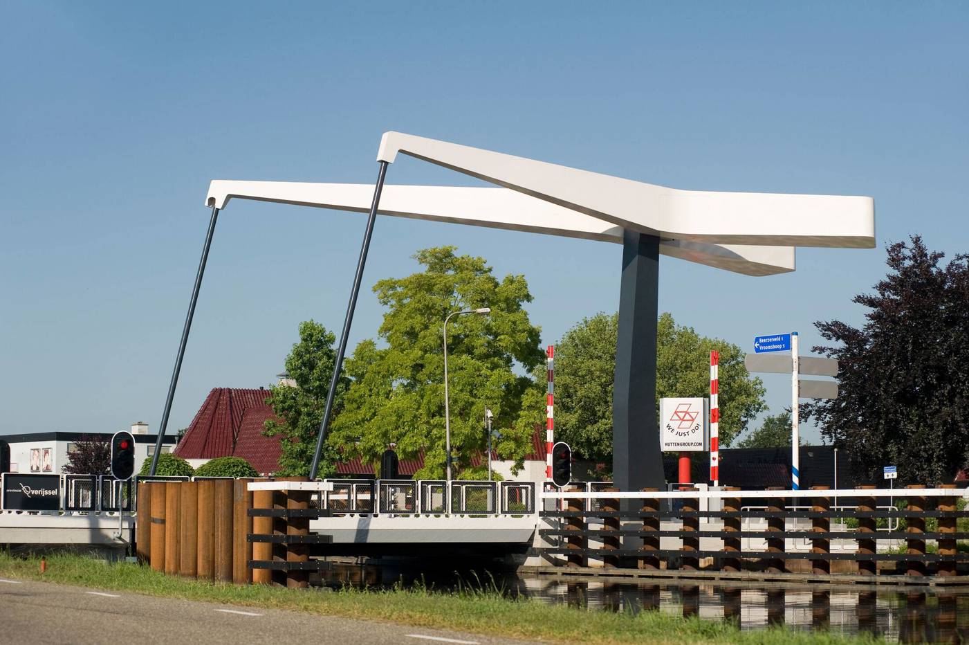 Moderne witte ophaalbrug over een kanaal bij een dorpsstraat.