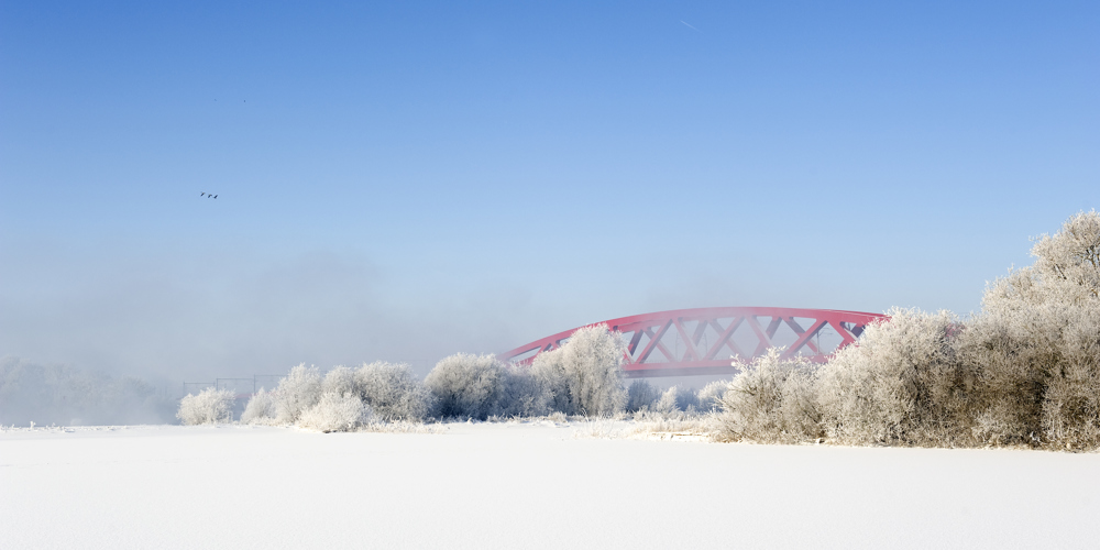 Winterfoto van rode brug in de sneeuw